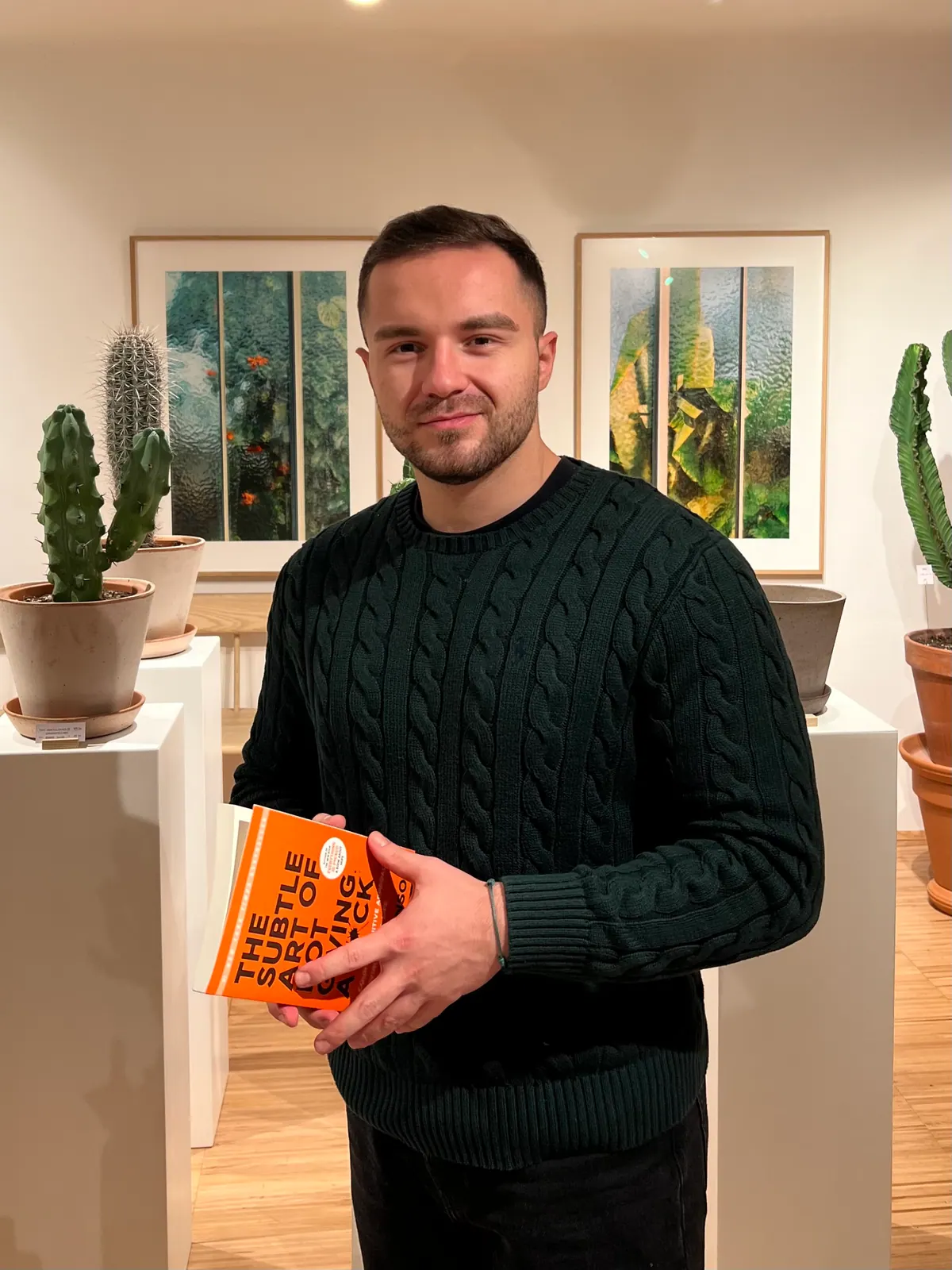 Loren Angoni holding a book in a dark green sweater.