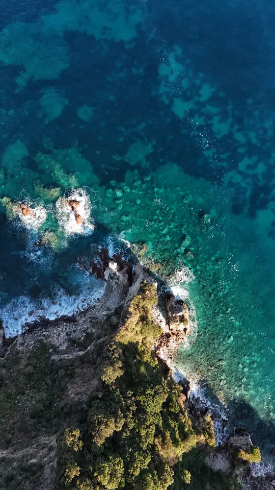 Vertical drone view of rocky shoreline and clear Albanian water.