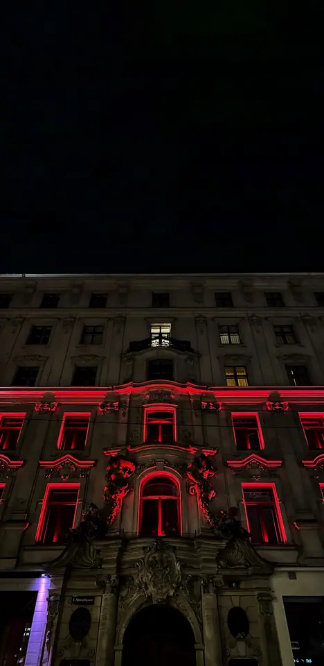 Night facade lit in saturated red against a dark sky.